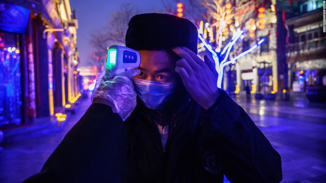 A worker has his temperature checked on a shuttered commercial street in Beijing on February 12.